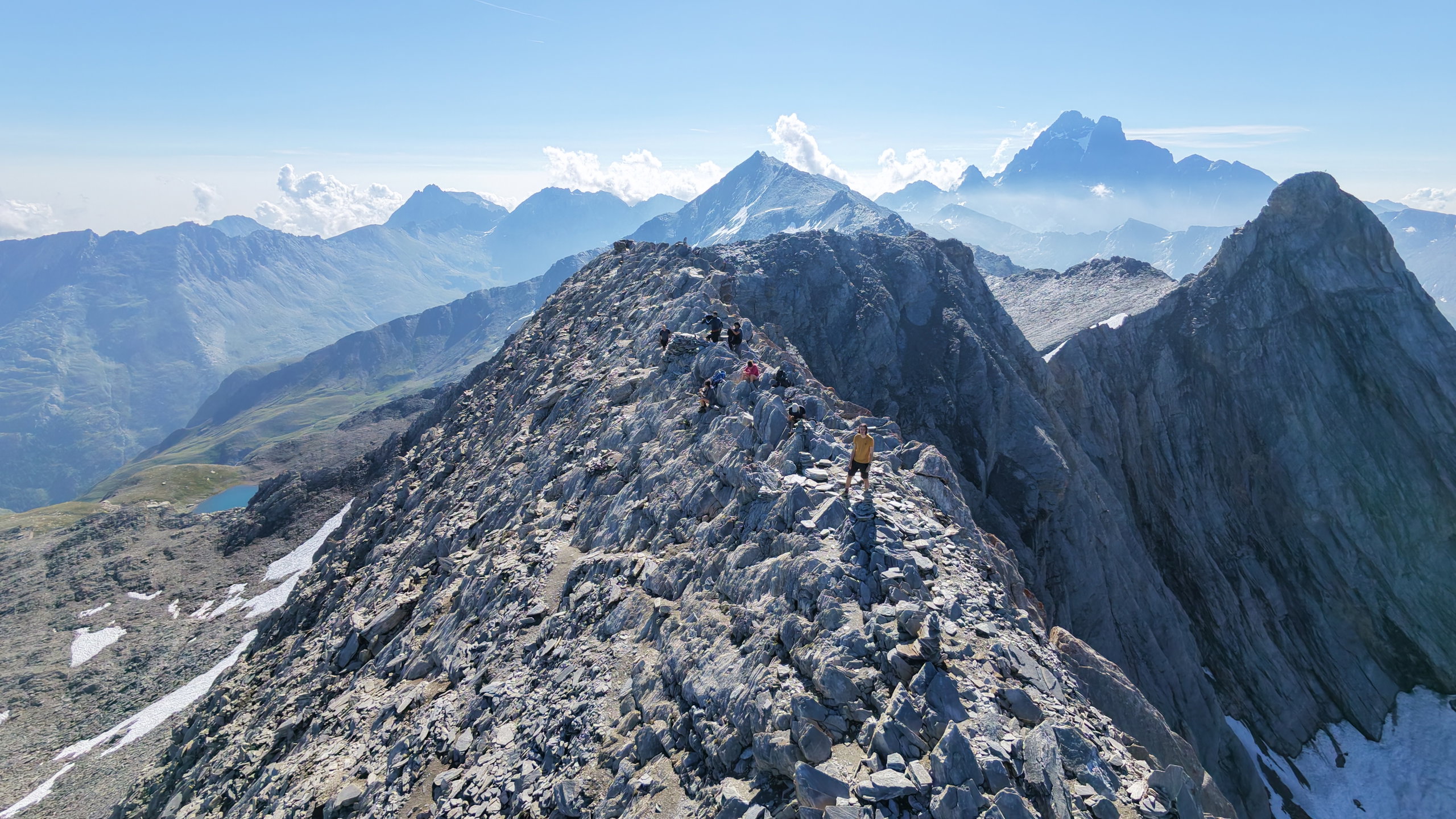 Rocky summit ridge of Pain de Sucre with layered alpine peaks stretching into the distance