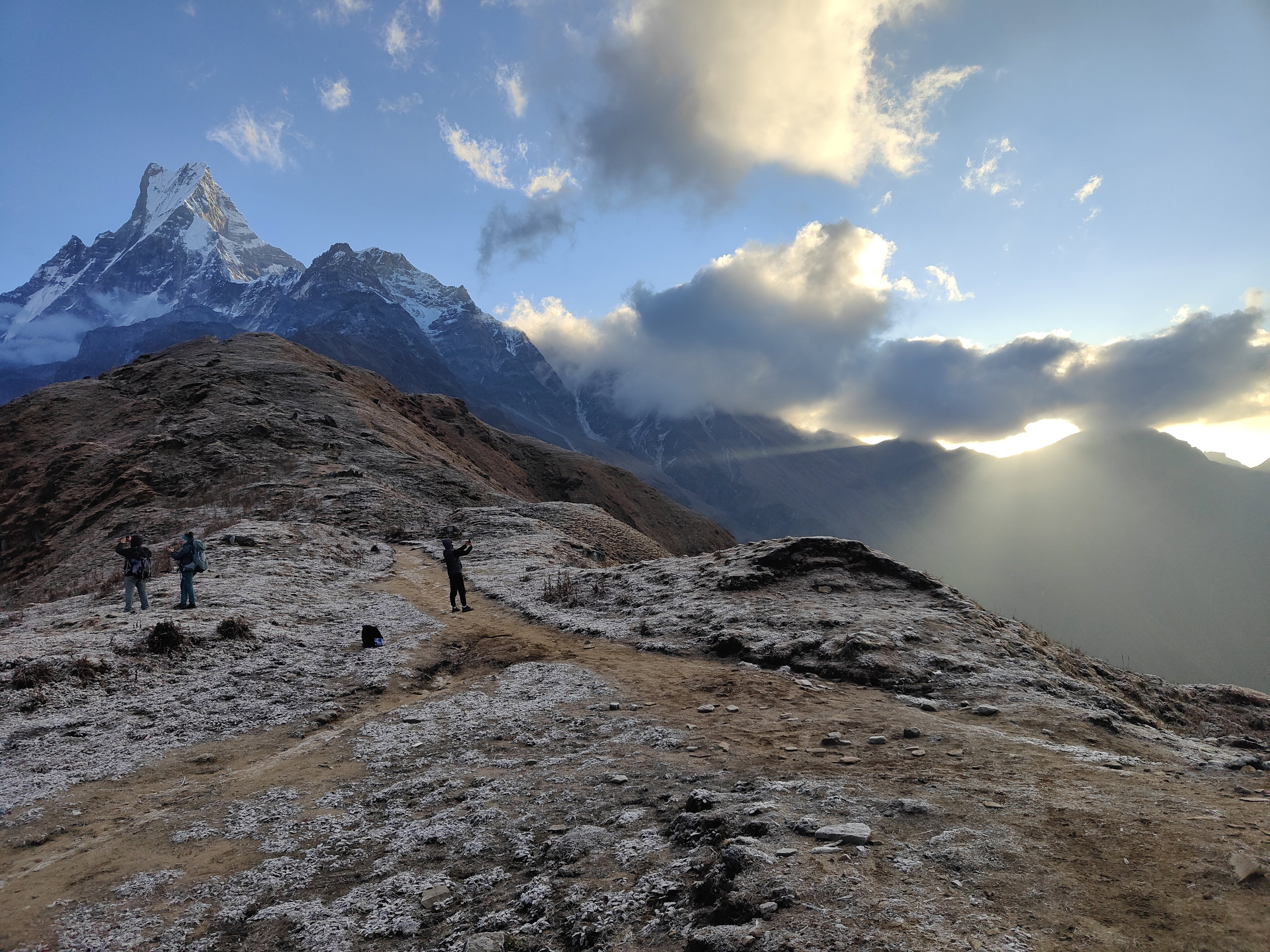 Hikers on the frost-covered ridge at Lower Viewpoint, facing Machhapuchhre
