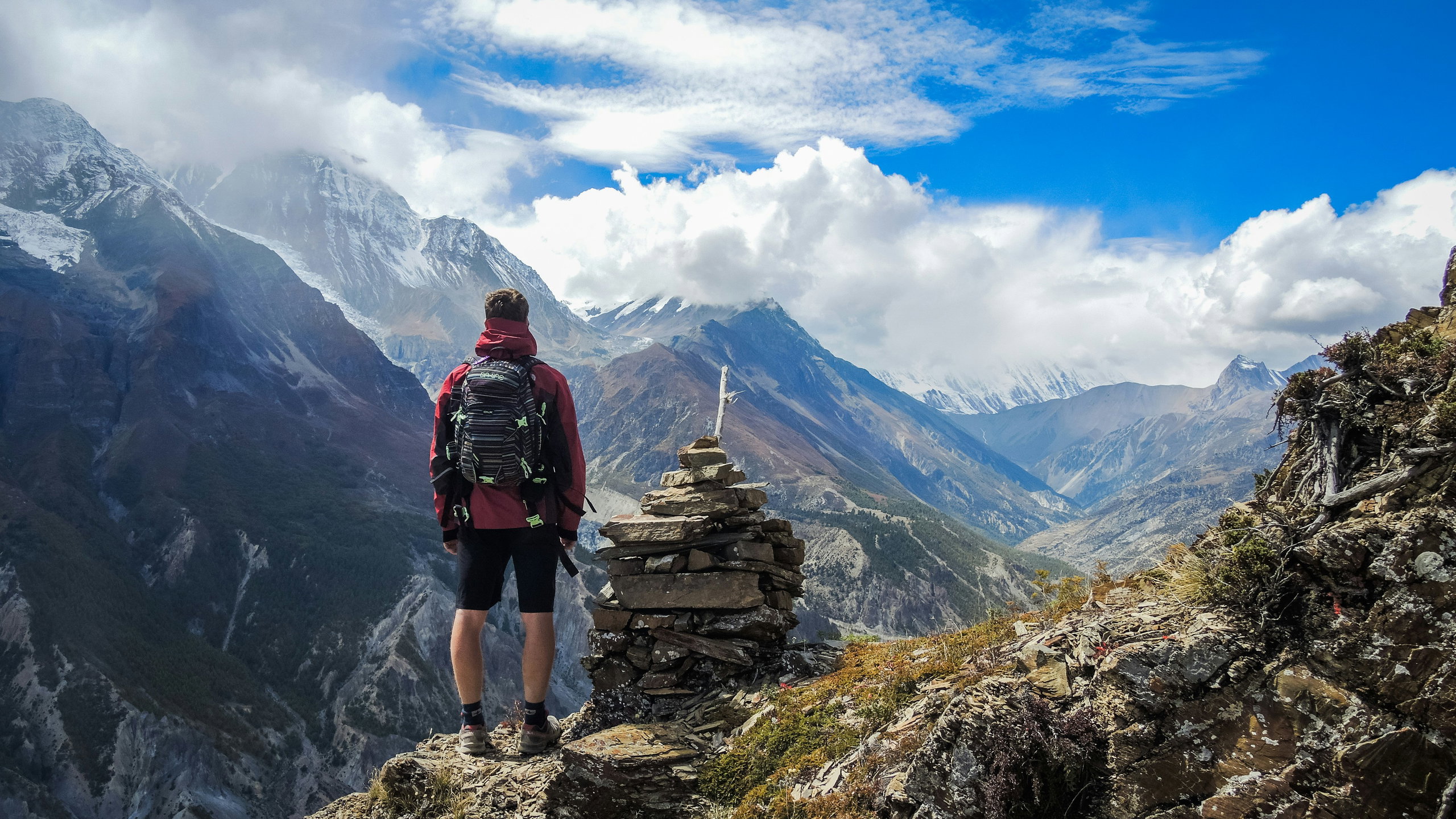 A hiker on a high-altitude trail near Ice Lake, looking out over the mountains and the Manang Valley.