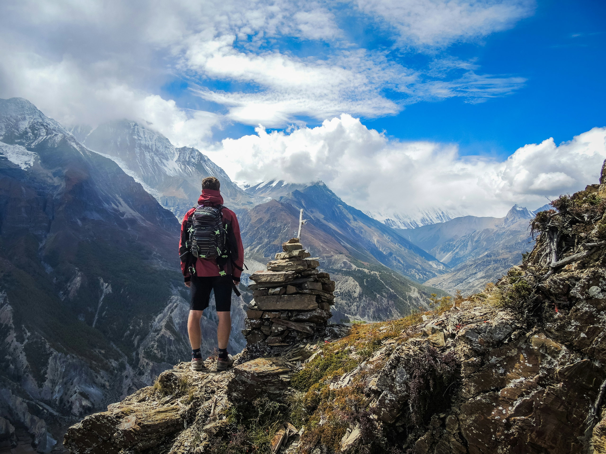 A hiker on a high-altitude trail near Ice Lake, looking out over the mountains and the Manang Valley.