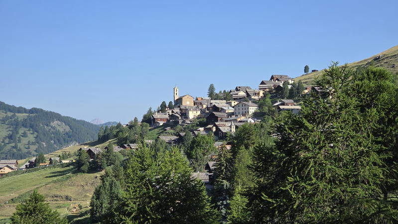 Saint Véran village climbing a sunny mountain slope.